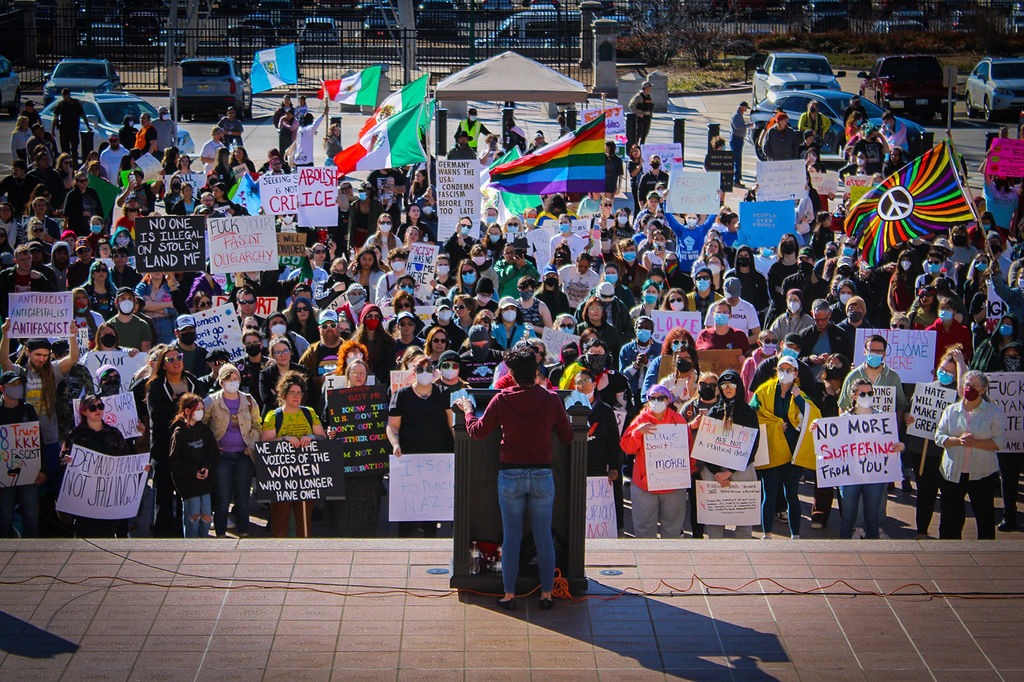 a woman standing in front of a crowd of people holding signs 